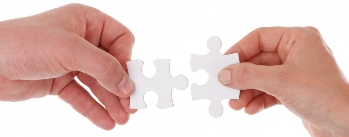 Photo of two hands holding puzzle pieces
